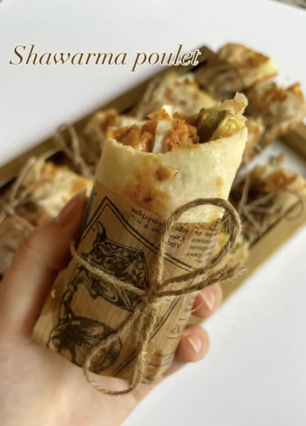 Shawarma poulet tenu à la main, ouvert sur sa garniture