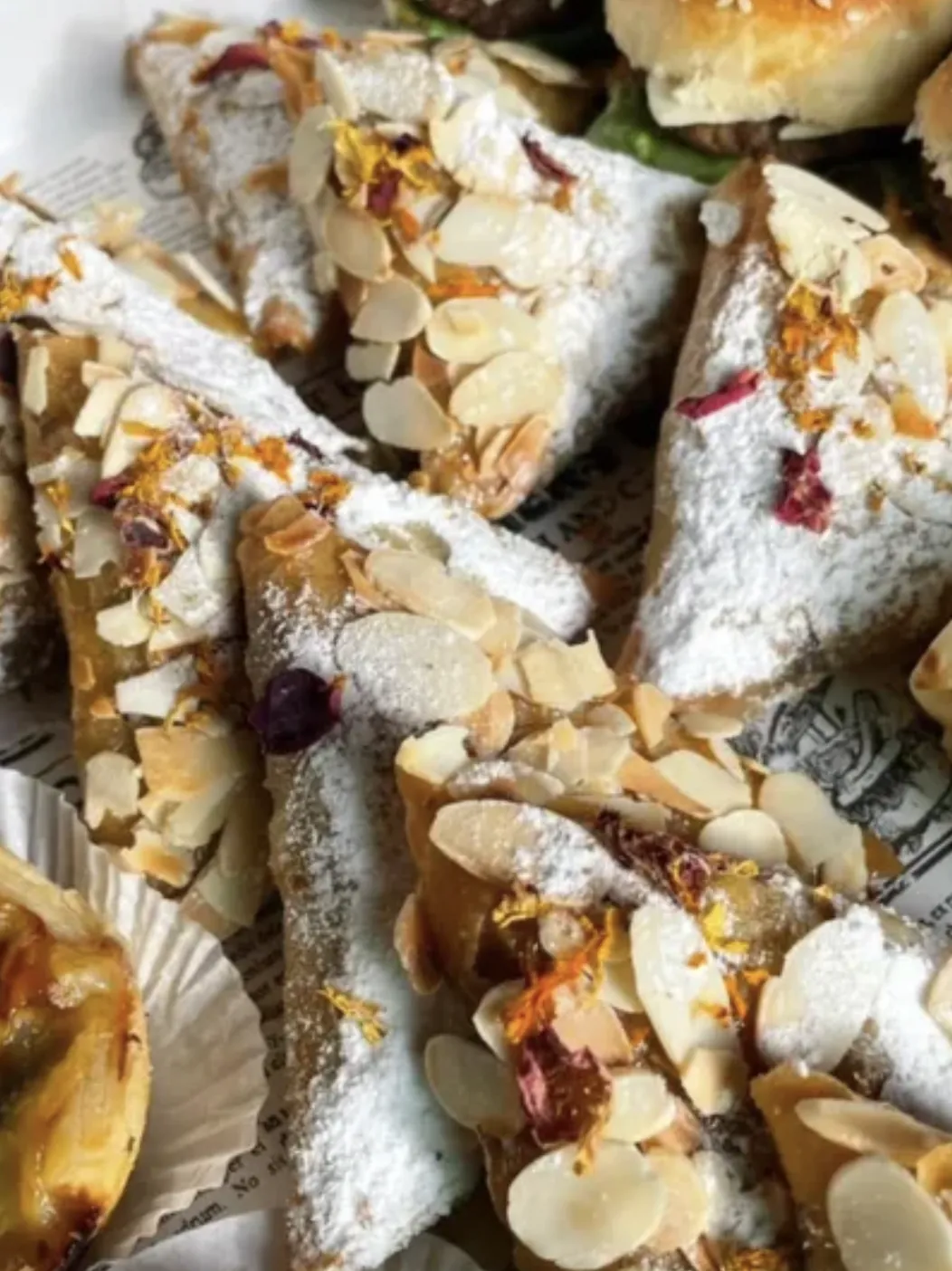 Triangles feuilletés aux amandes, sucre glace et pétales de fleurs