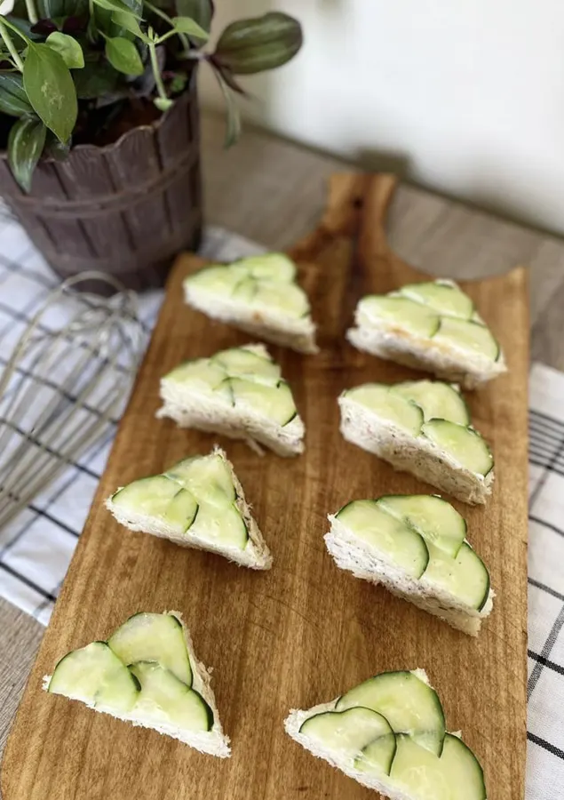 Triangles de mini sandwiches au concombre alignés sur la planche