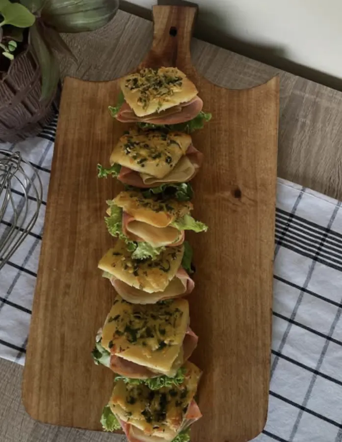 Six mini sandwiches gratinés alignés avec herbes fraîches